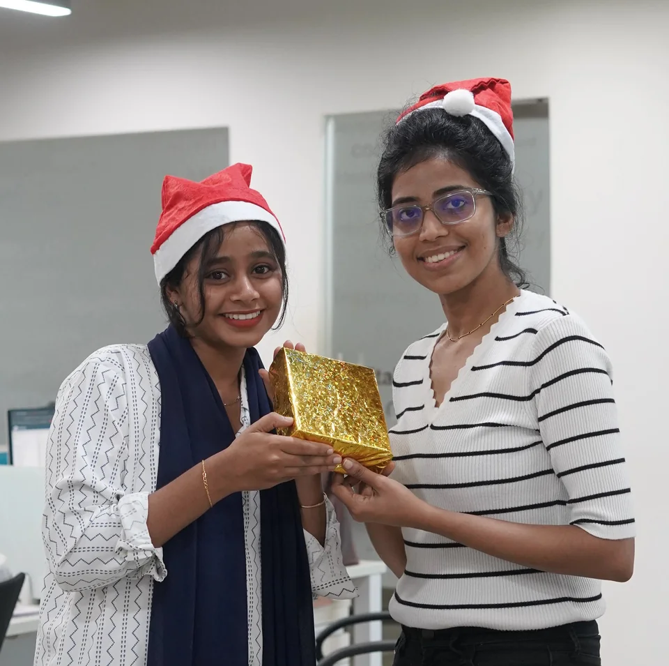 Two teammates exchanging a wrapped gift at Christmas
